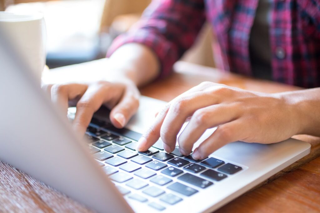 Close up of man typing on laptop